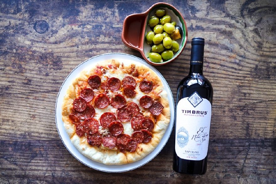 Eine Pizza und eine Flasche Wein auf gedeckten Tisch